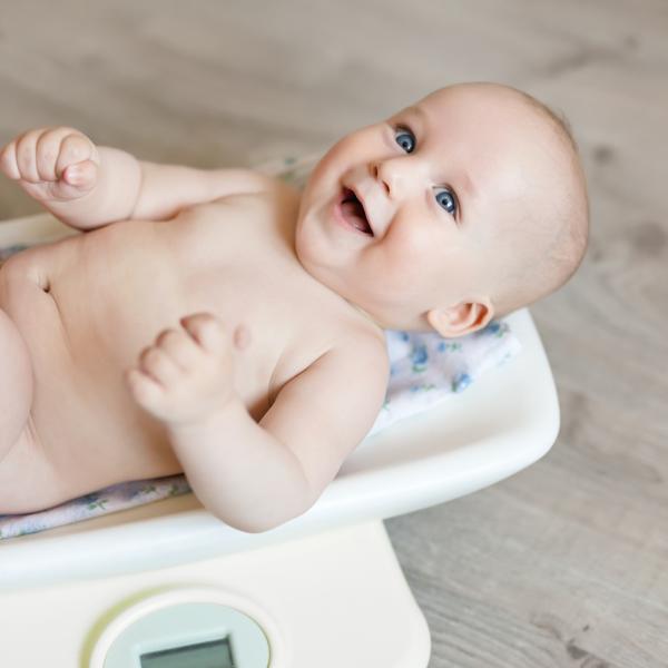photo of a happy baby being weighed on scales