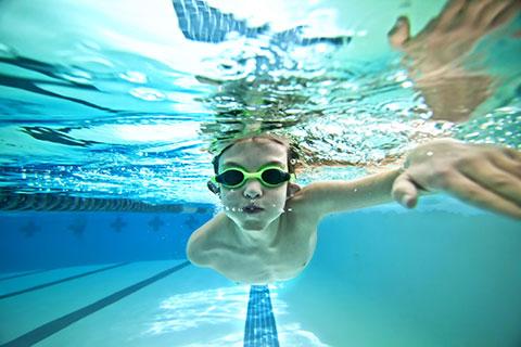 underwater photo of boy with googles swimming