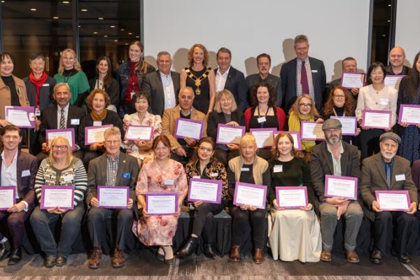 A formal photograph of Councillors and all the grants recipients in a group with the grants recipients holding their certifcates of appreciation