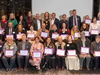 A formal photograph of Councillors and all the grants recipients in a group with the grants recipients holding their certifcates of appreciation