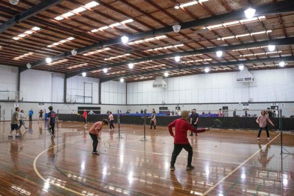 photo of a group of older people playing badminton in an indoor court