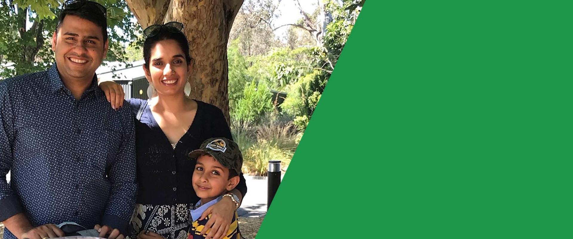 Young Indian family standing and smiling in front of tree