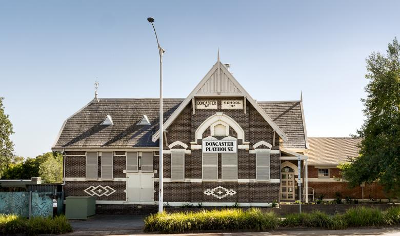 A brown and white tiled historic building with a large pitched roof. Signs on the building read "Doncaster School No 197" and "Doncaster Playhouse".