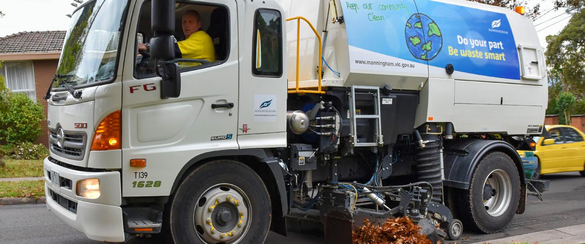 street sweeper sweeping up leaves on road