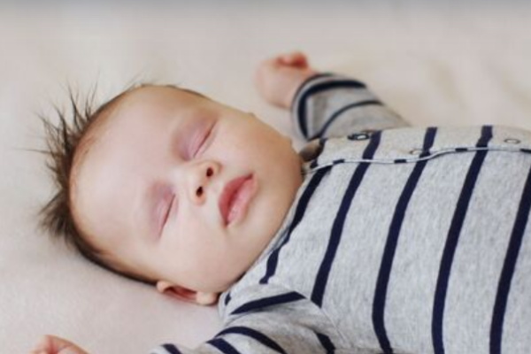 Sleeping baby lying on back with arms up beside their head